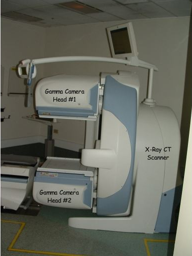 Labeled hybrid SPECT CT scanner showing detector heads, CT gantry and patient table